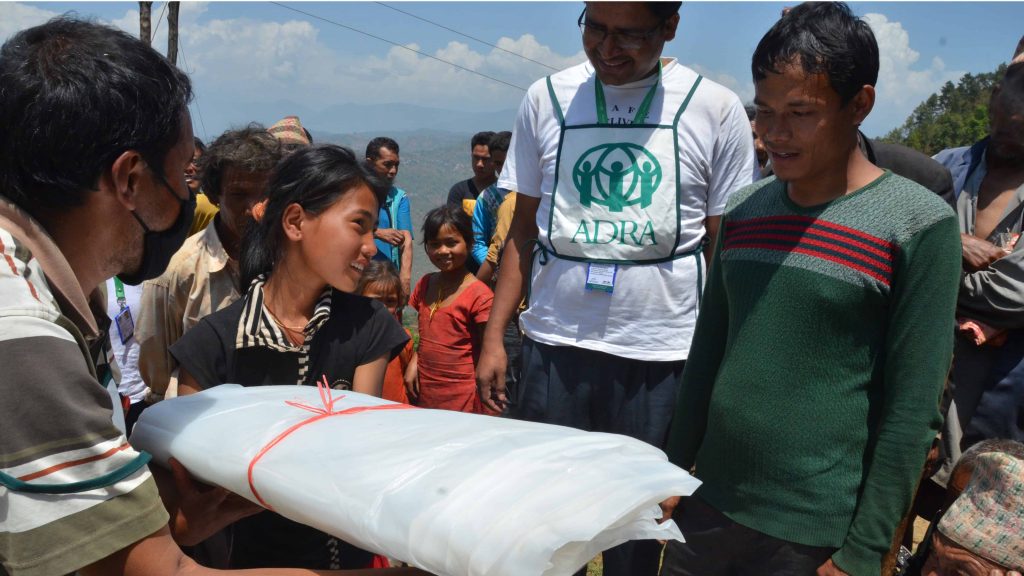 Girl accepts a tarp on behalf of her family in Nepal.