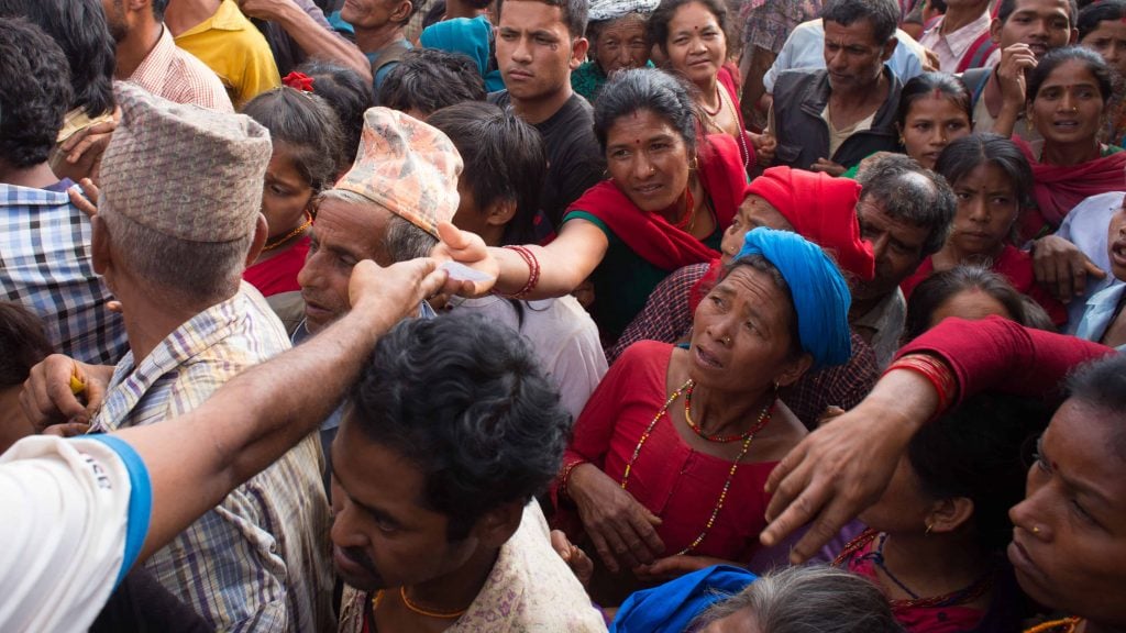 Nepalese gather around to receive relief supplies