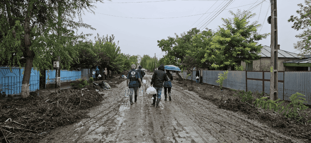 A group of ADRA team members walk down a flooded dirt road.