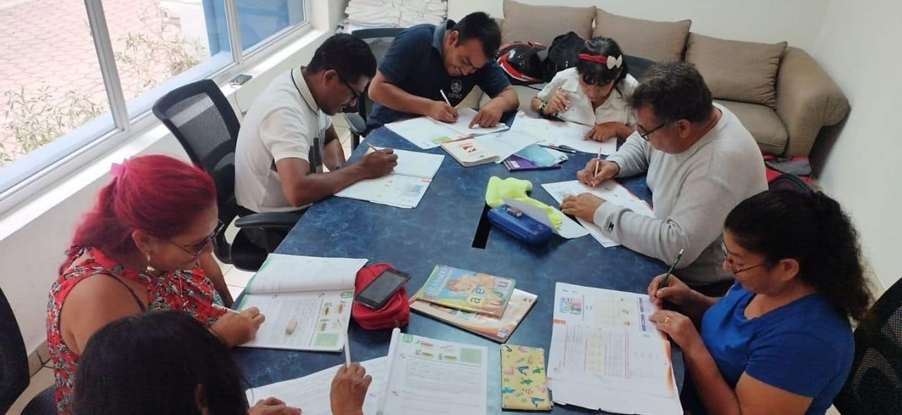 In El Salvador, a group of people are at a table, learning to read and write