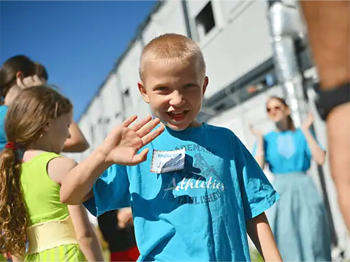 Happy boy waving at community event supporting children’s health and education.