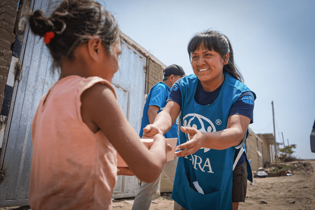 ADRA volunteer helping a young girl in a community outreach program.