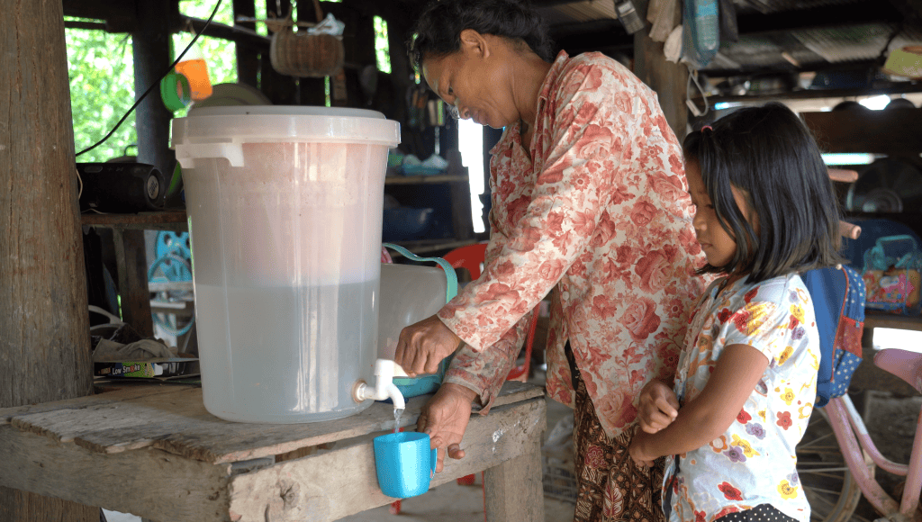 Clean water being accessed by a woman and child in a rural setting, supported by ADRA International.