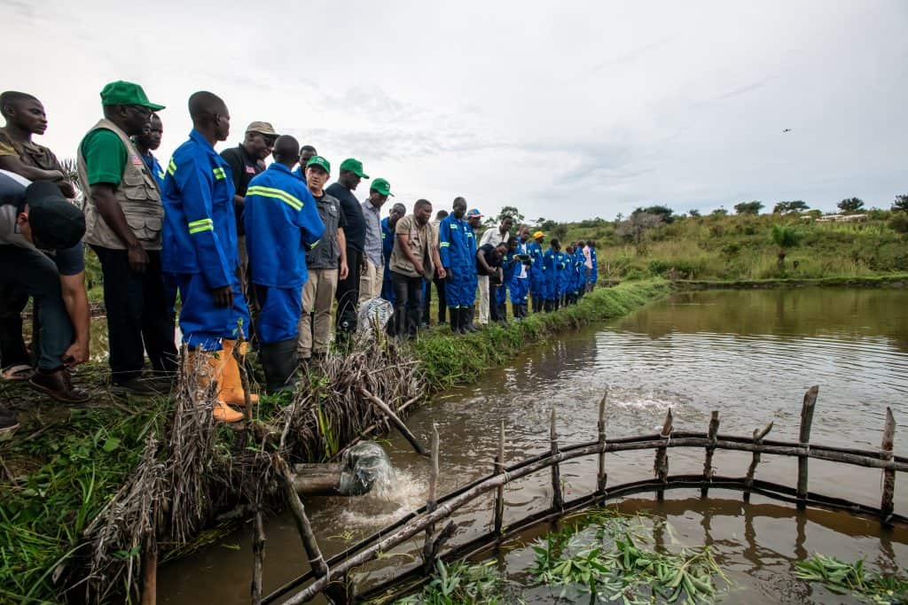 Community members gather near a water source in a rural area for water access and sanitation efforts.