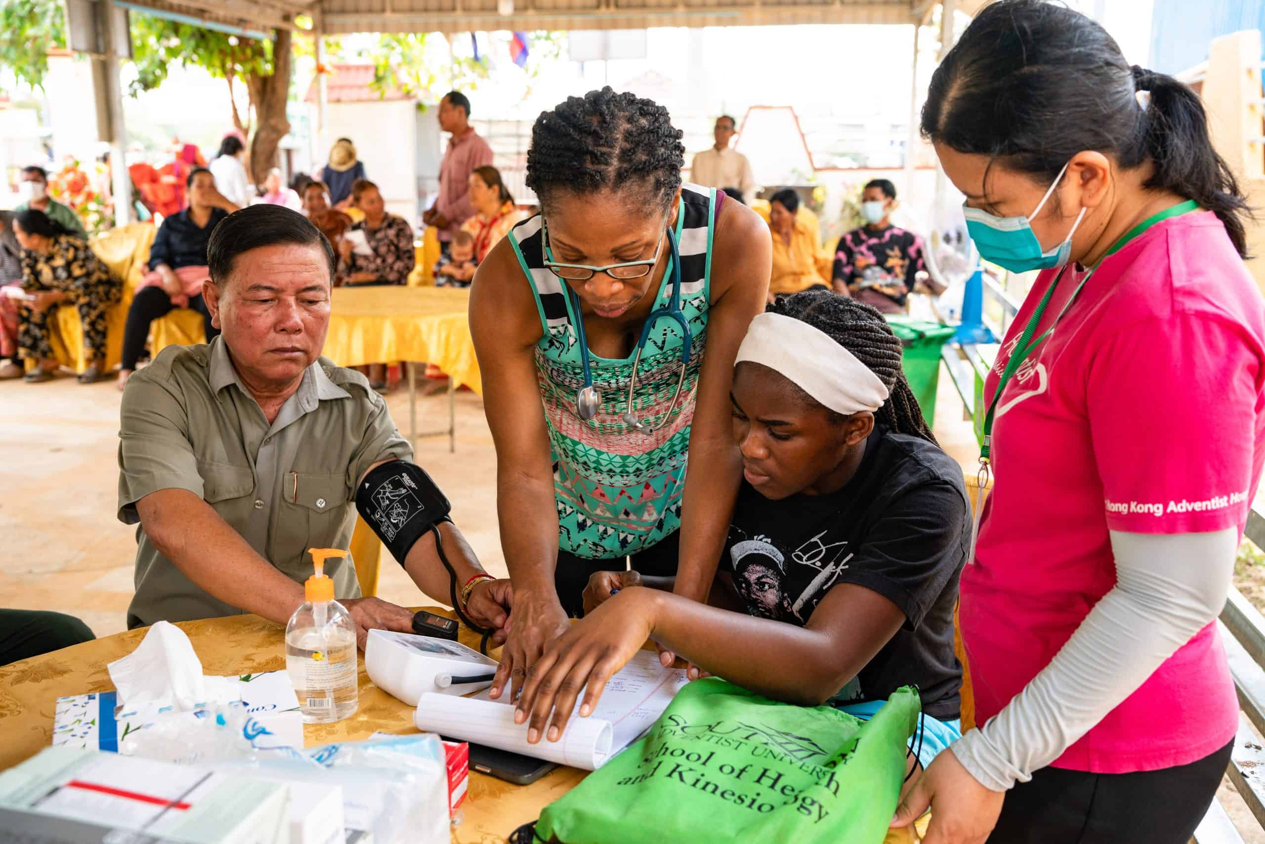 Healthcare workers assist a woman with her blood pressure at a community health event.