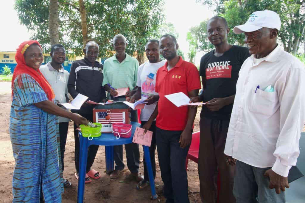 Community health education session outdoors with local leaders and health workers.