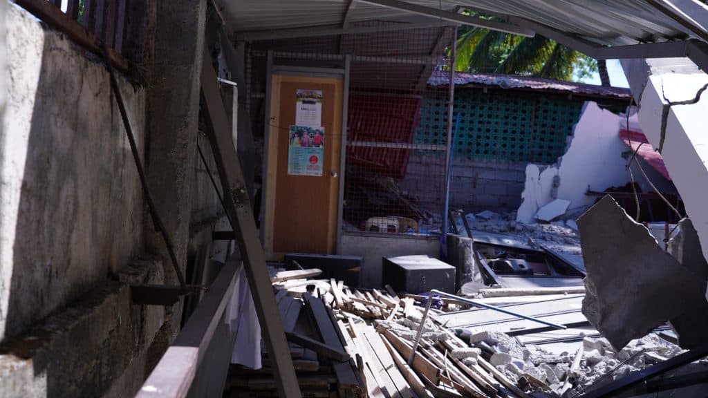 A damaged building with debris and collapsed roof after disaster, ADRA International relief efforts.