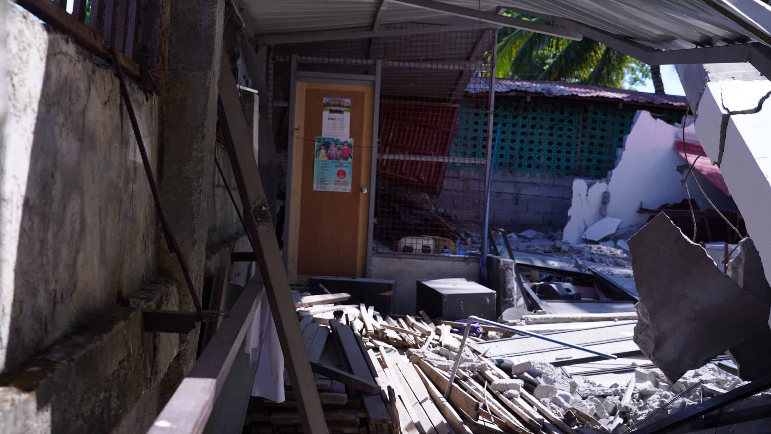 A damaged building with debris and collapsed roof after disaster, ADRA International relief efforts.