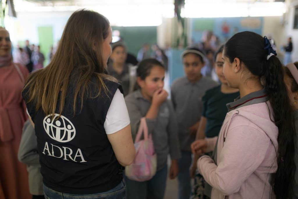 ADRA worker engaging with refugee children at a community event.